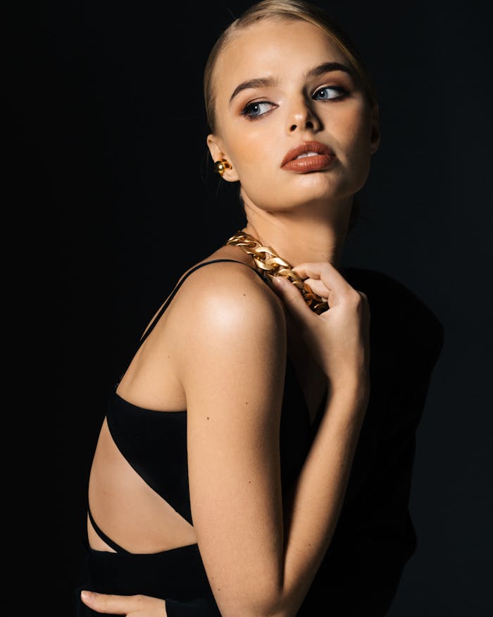 Stylish woman in a black outfit with a gold chain necklace, exuding sophistication and elegance.