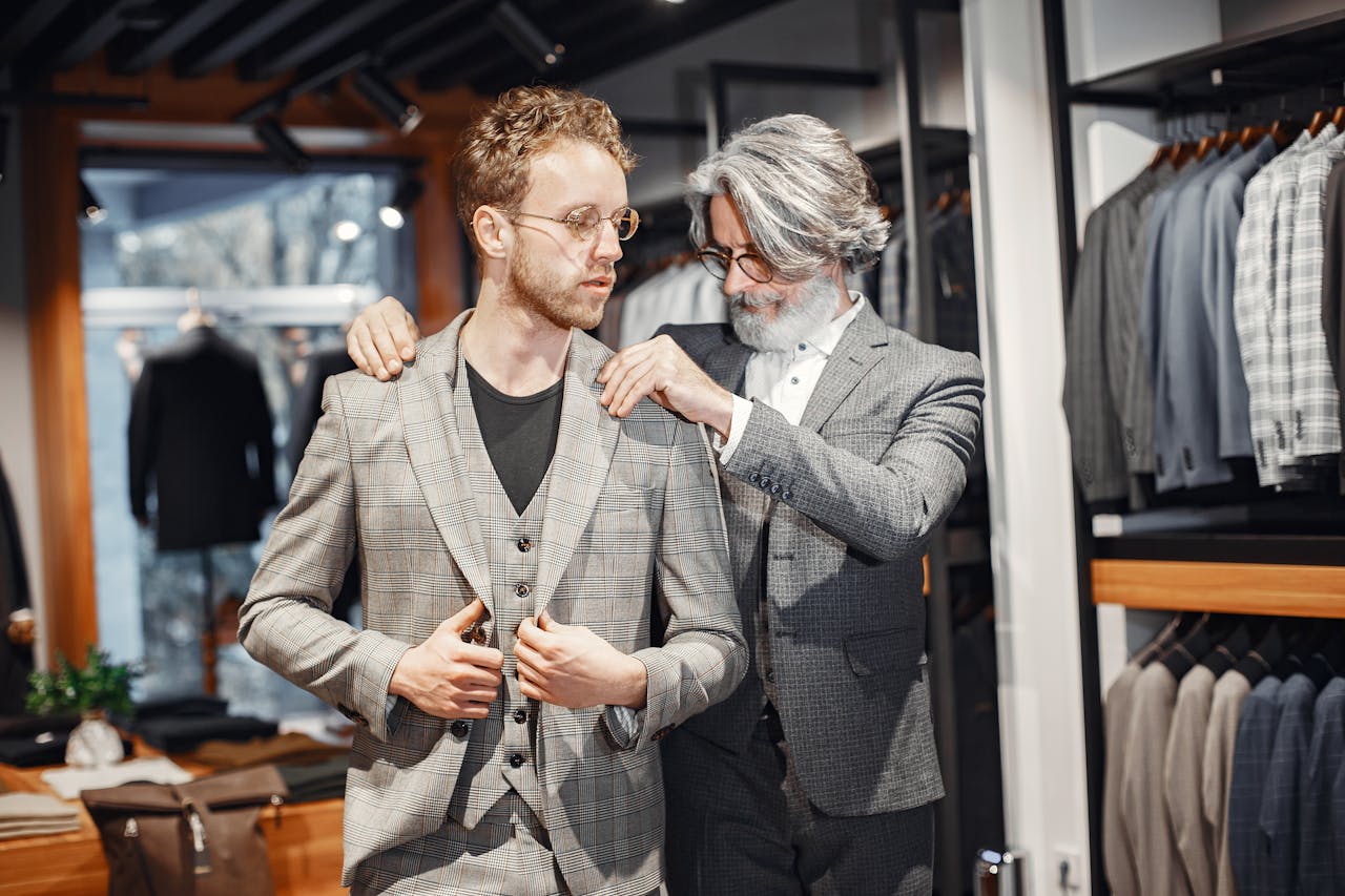 A tailor adjusts a suit for a client in a stylish boutique setting.